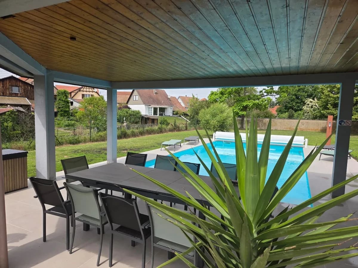 Piscine et terrasse de Villa La Digue à Plobsheim, avec les arbres du jardin en arrière-plan