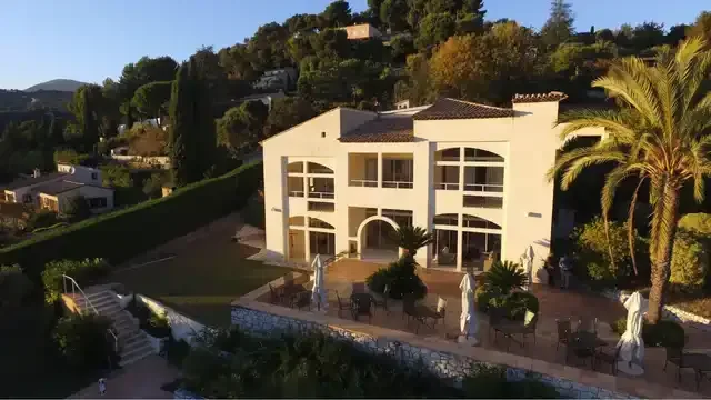 Façade de Villa St. Maxime éclairée par le soleil couchant, entre les palmiers