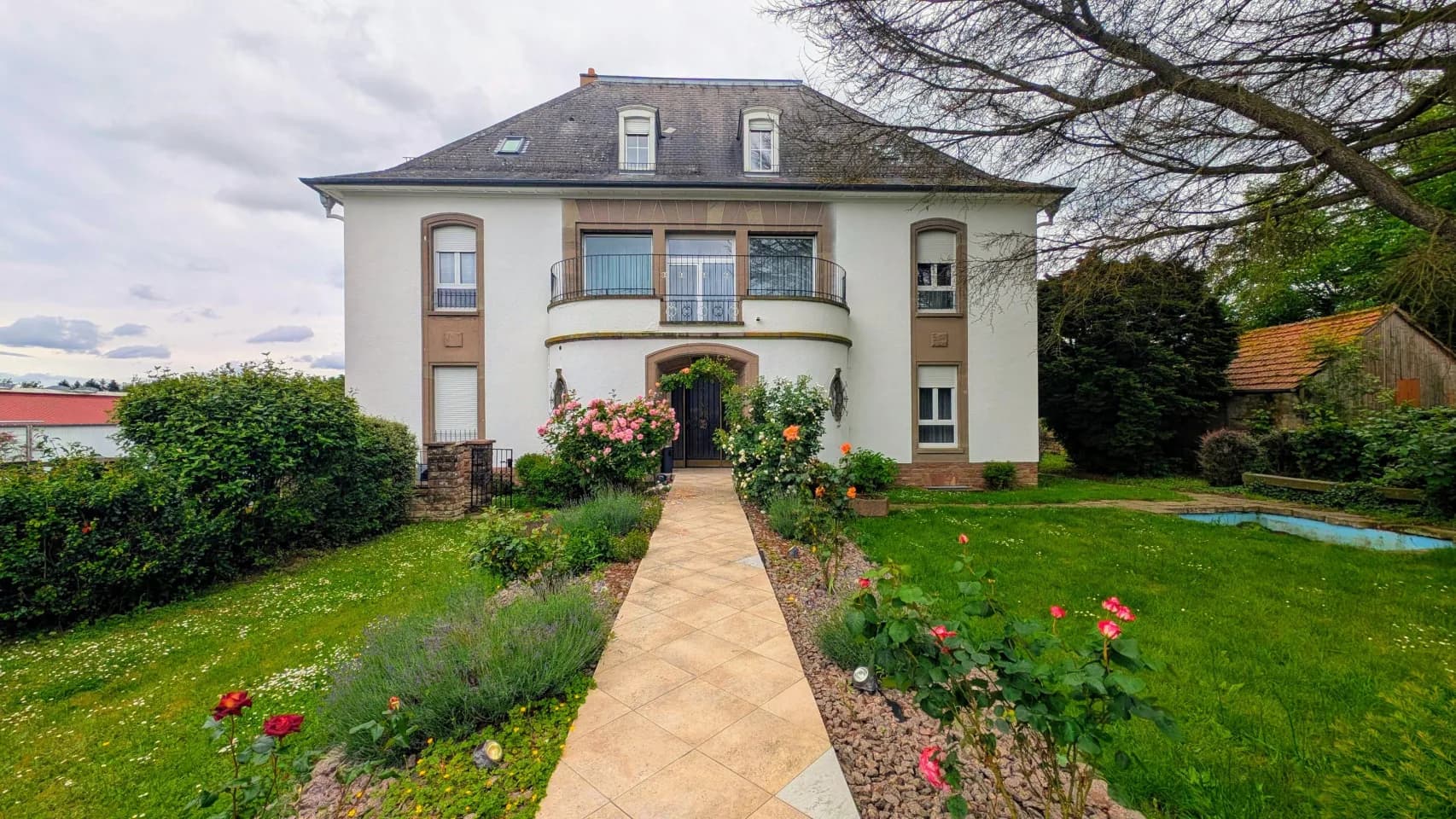 Domaine La Rosière à Diemeringen, façade blanche, balcon arrondi et allée entre les rosiers